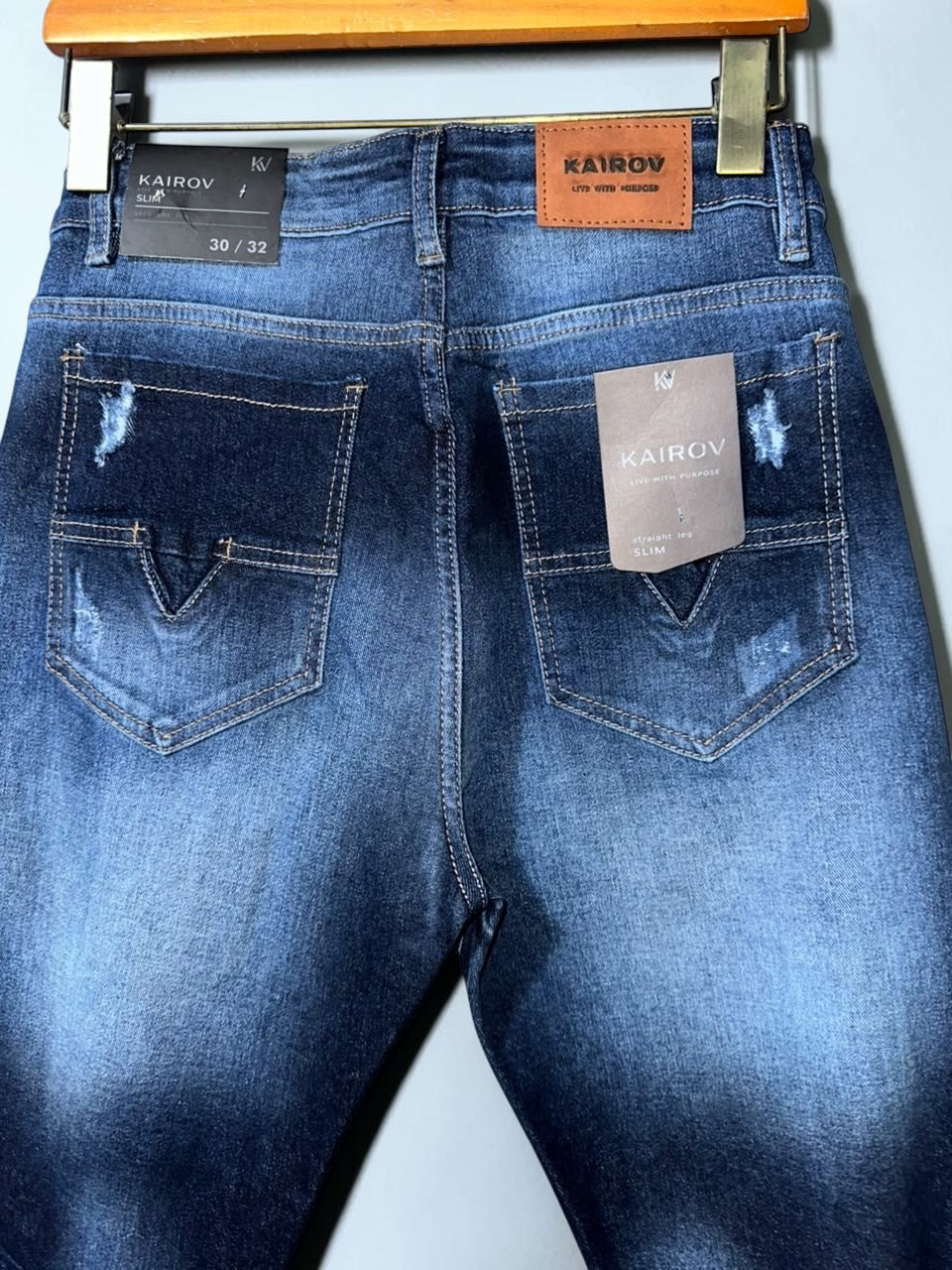 Jeans Mi tienda KAIROV de mezclilla azul con efecto deslavado, corte slim y detalles desgastados en bolsillos traseros.