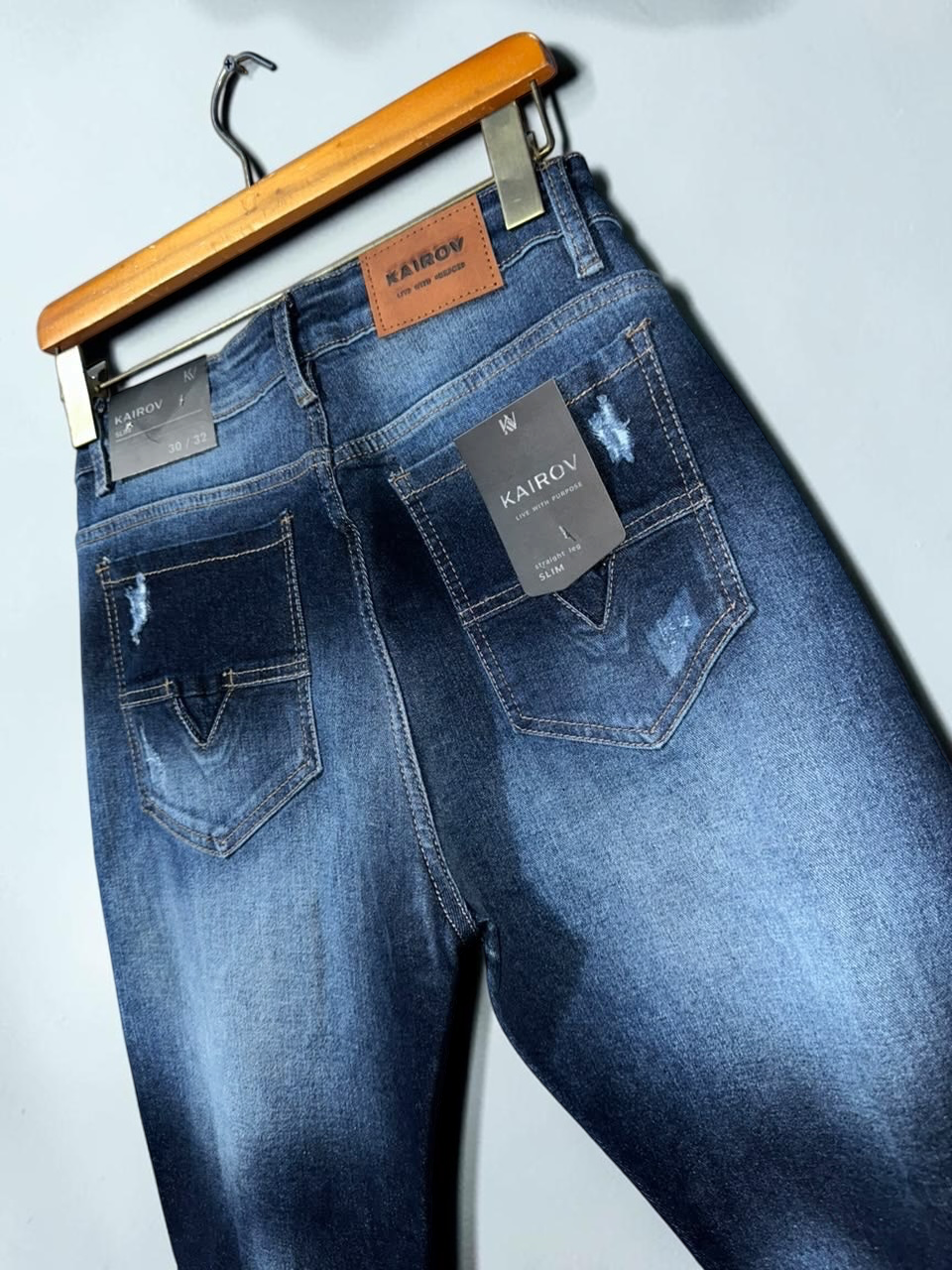 Jeans Mi tienda KAIROV de mezclilla azul con corte slim, detalles desgastados y etiqueta de cuero en la parte trasera