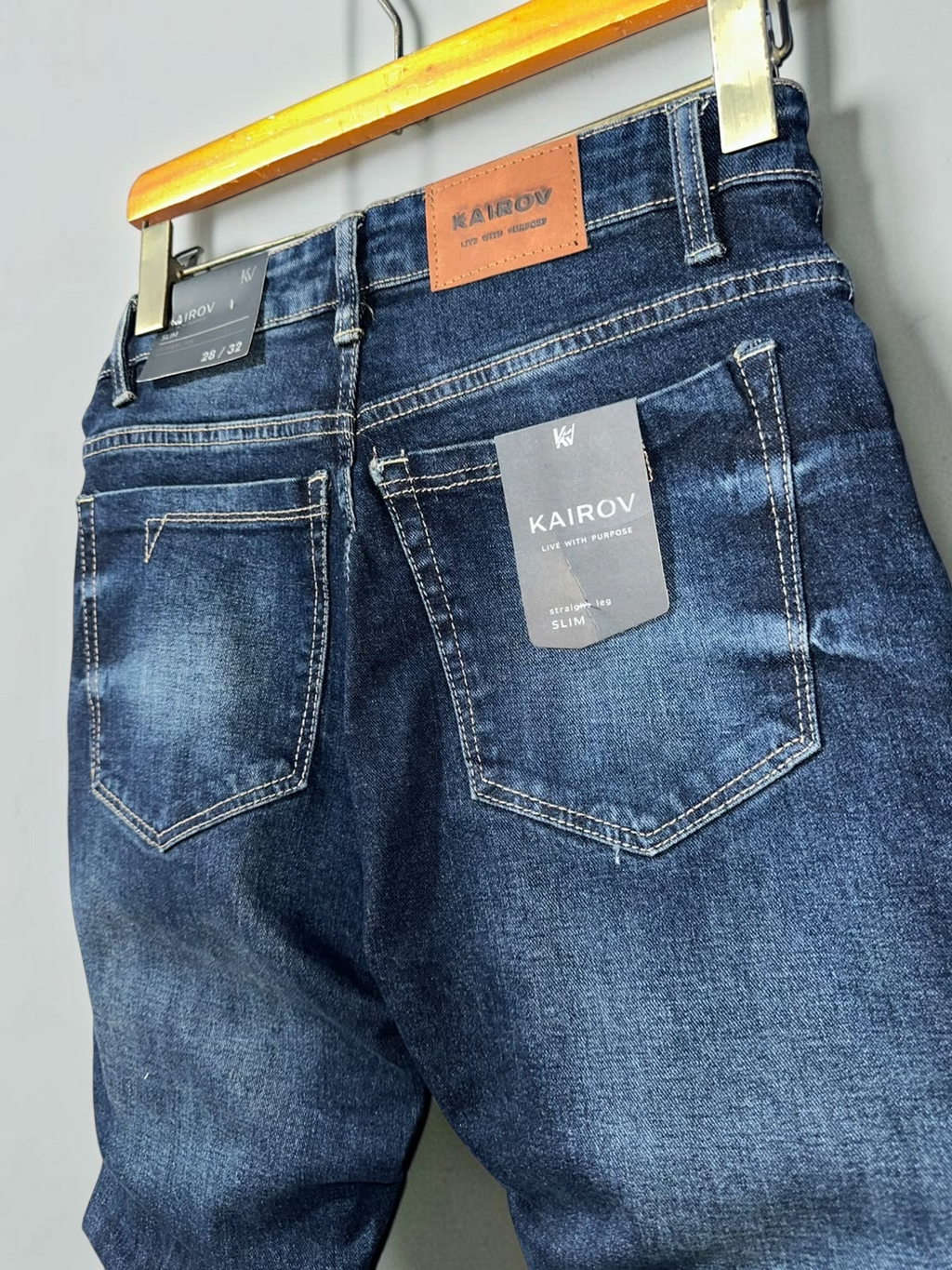 Jeans KAIROV de corte slim en mezclilla azul profundo con deslavado, costuras en contraste y etiqueta de cuero Mi tienda