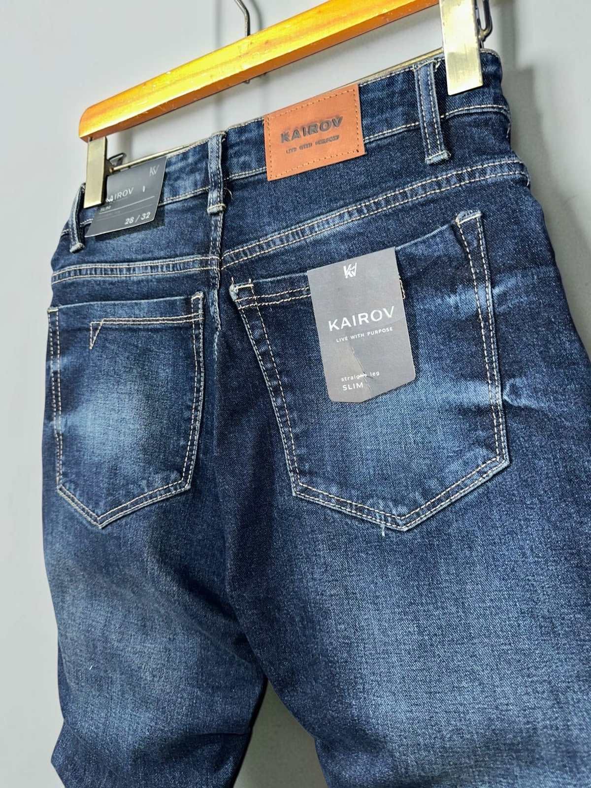 Jeans KAIROV de corte slim en mezclilla azul profundo con deslavado, costuras en contraste y etiqueta de cuero Mi tienda
