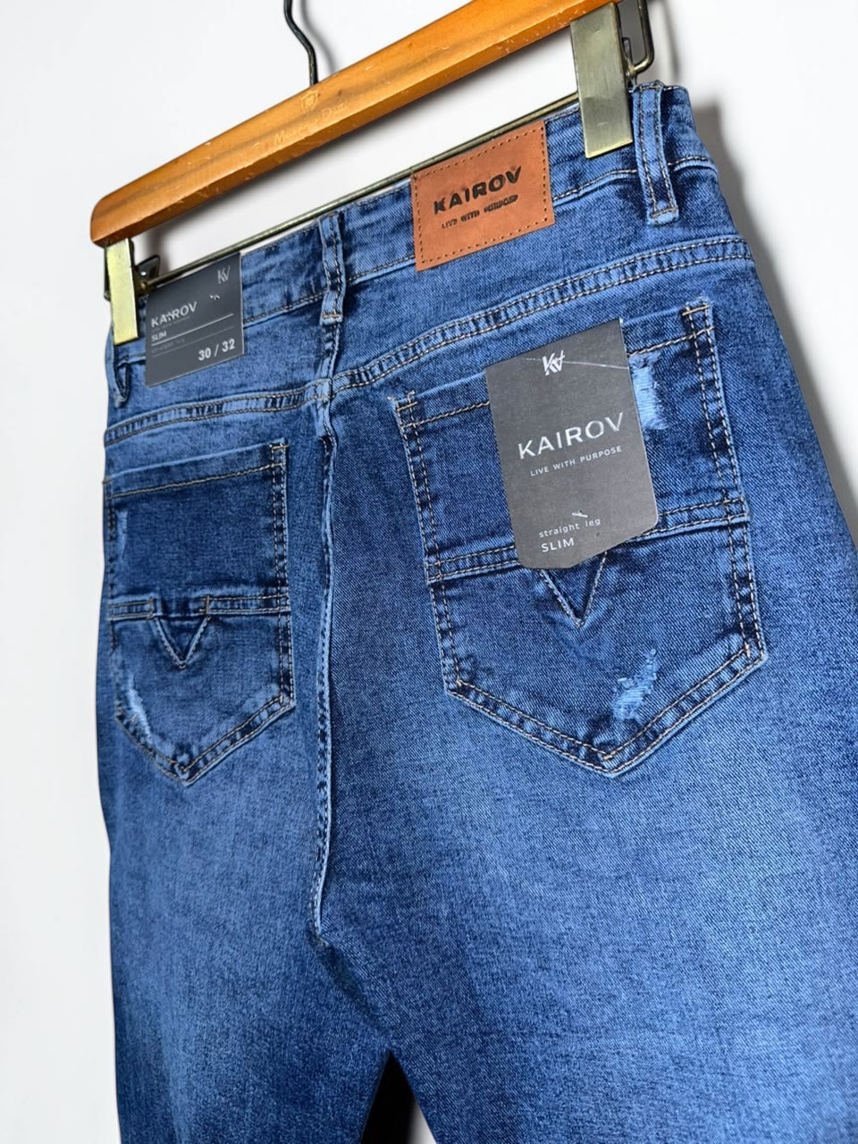 Jeans slim fit Mi tienda KAIROV en mezclilla azul medio con deslavado, rasgaduras y etiqueta de cuero en la cintura.